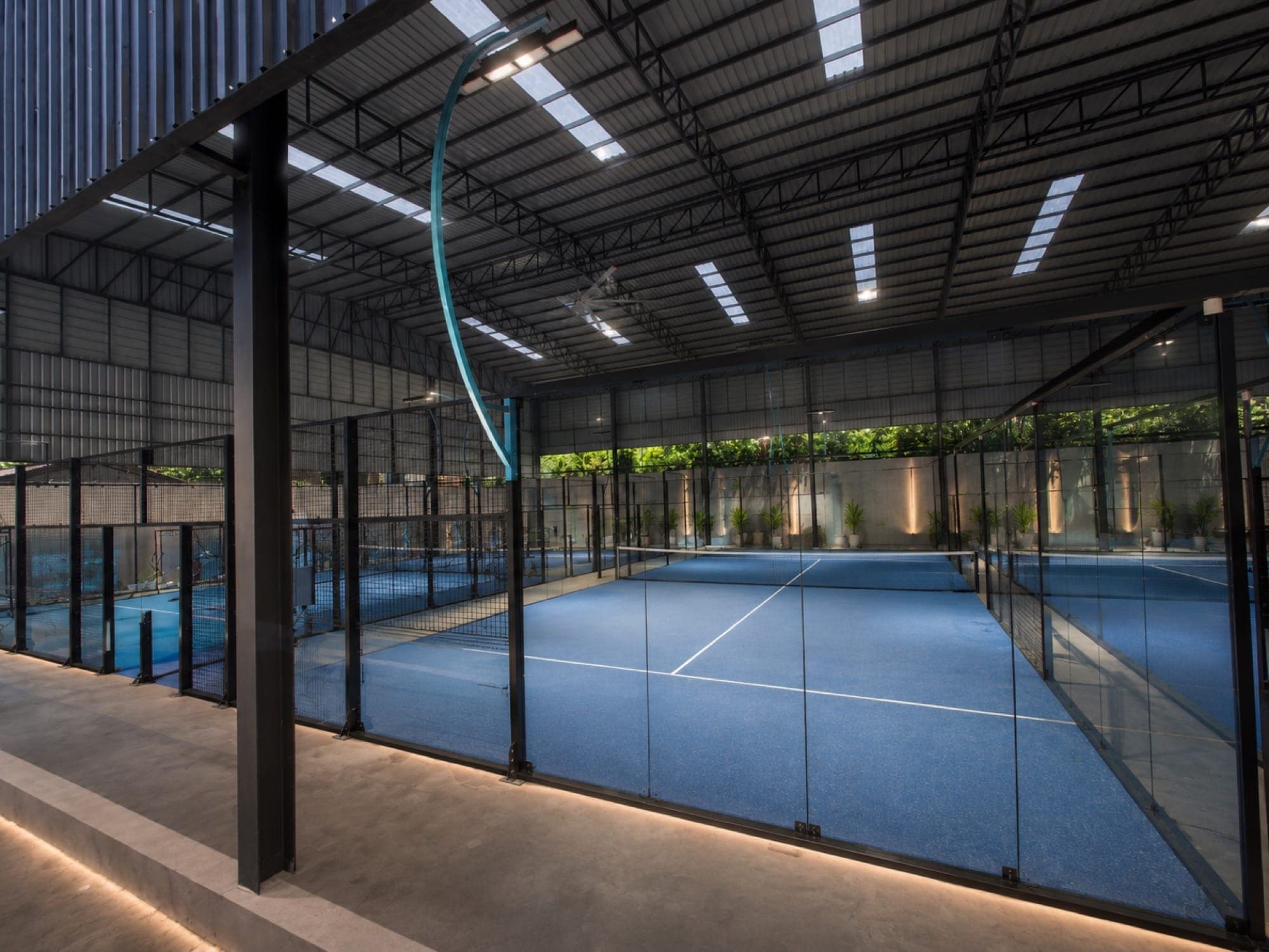 Covered super-panoramic padel courts inside the glass-walled hall
