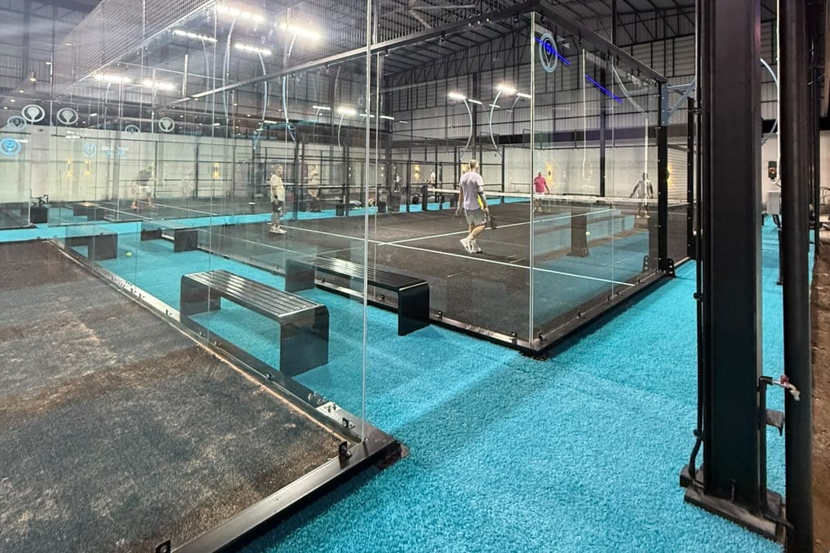 Games in progress in the covered hall, on black courts with cyan surrounds